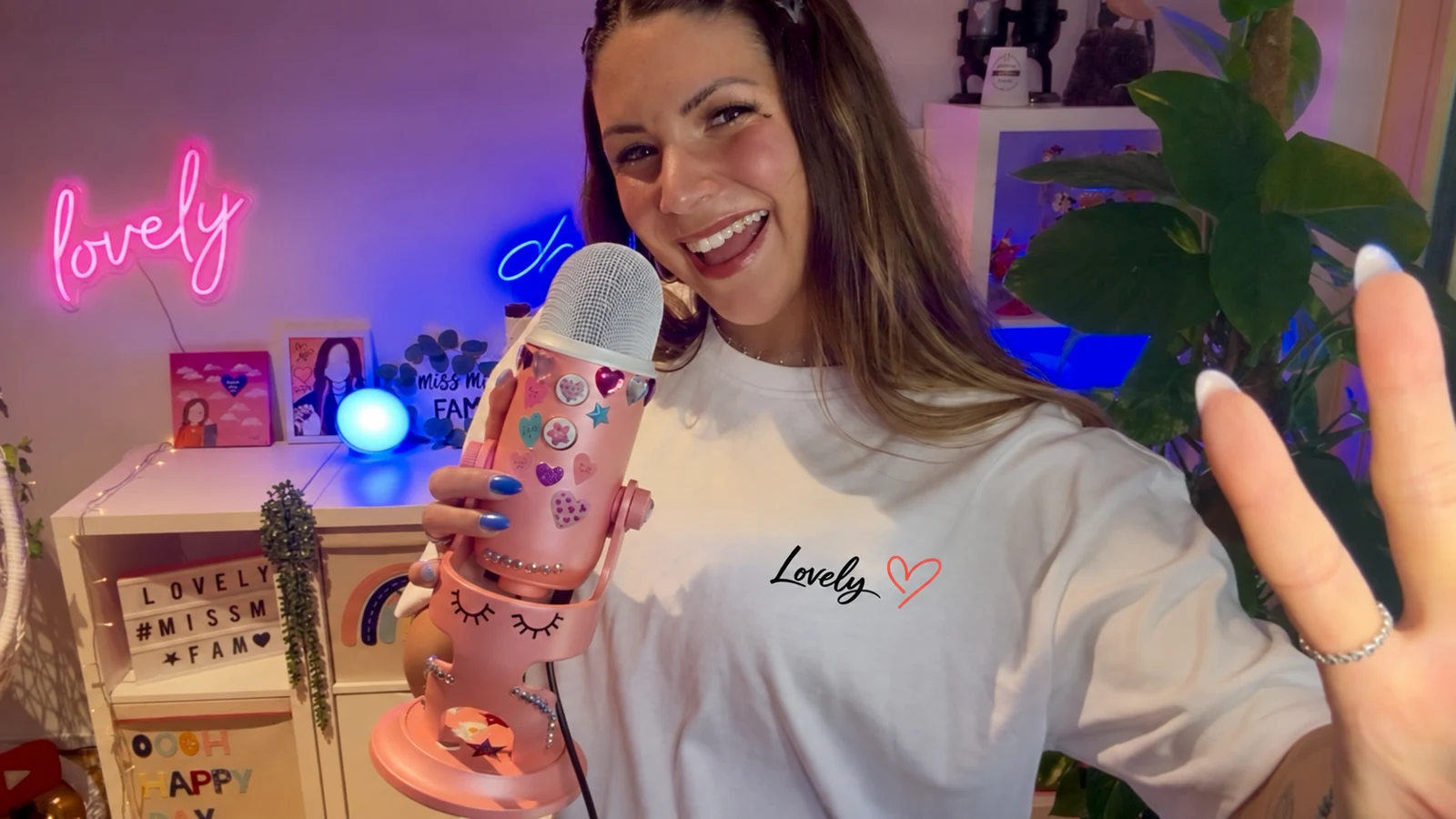 Miss Mi zeigt Peace mit ihrem rosa Mikrofon; neues Lovely-Motiv als digitale Anprobe.